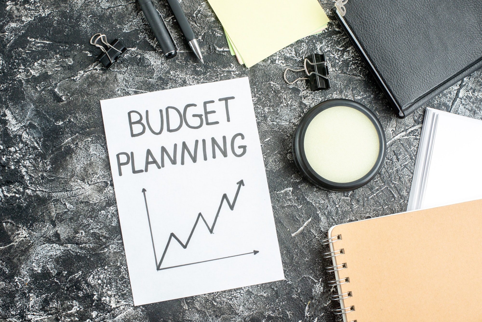 top view budget planning note with pens and copybooks on gray background job copybook school student